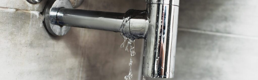 Understanding Leaking Pipes: A Comprehensive Guide to Common Causes 1 Damaged steel pipe with water drops on grey background