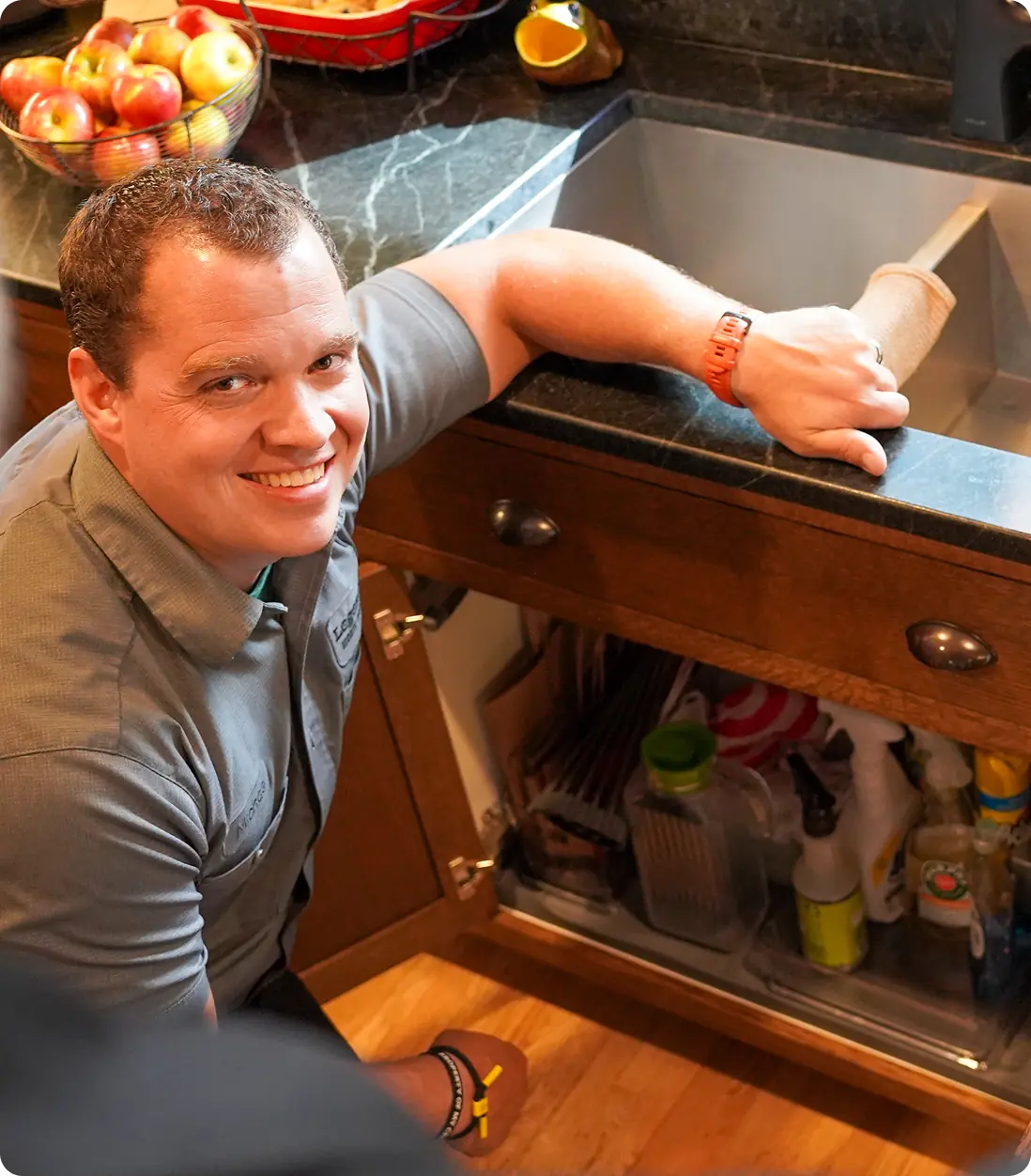Technician smiling while working under bathroom sink cabinet