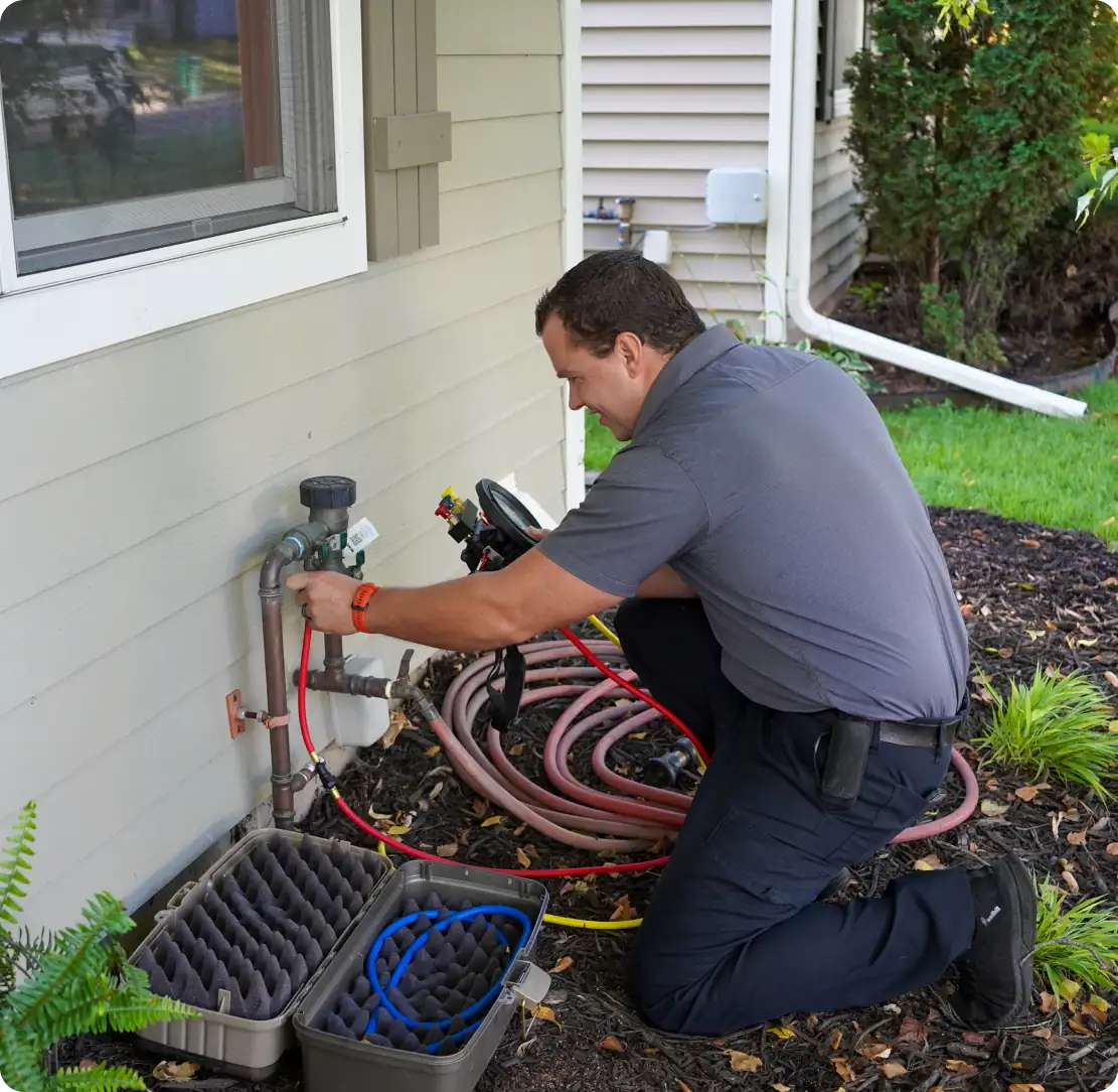 Licensed plumber working beneath bathroom sink on drain line