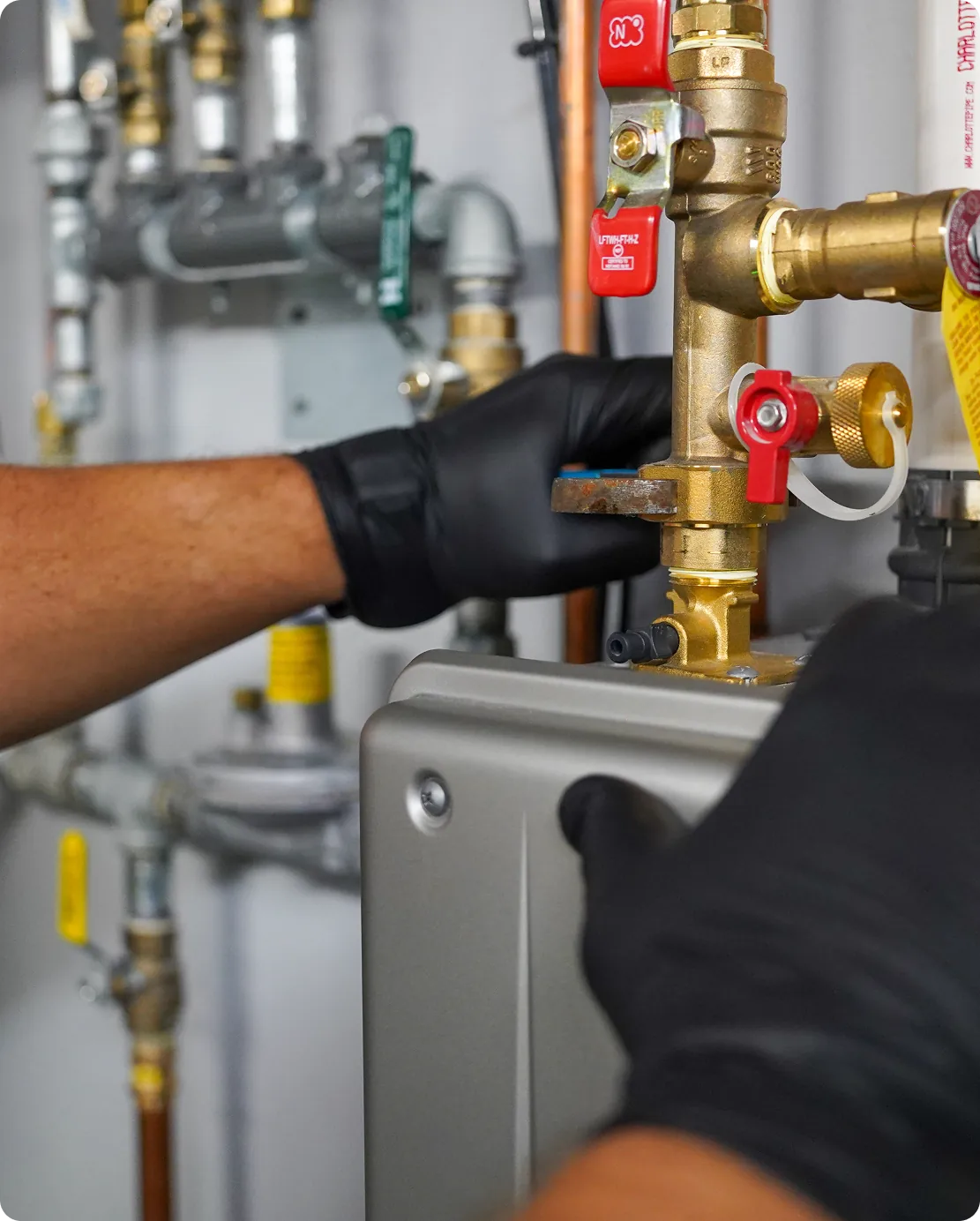 Technician tightening brass plumbing fittings in utility room